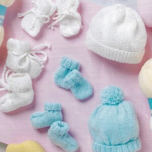 May include: A set of knitted baby items including two pairs of booties, two pairs of socks, and two hats. One hat is white and the other is light blue with a white pom-pom.