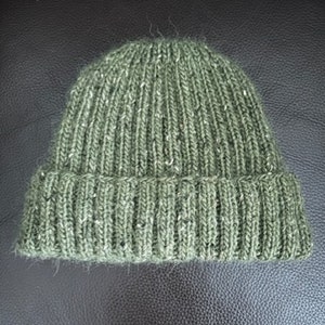 May include: A green knitted beanie hat with a ribbed texture.