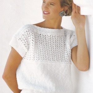 May include: White knitted top with a lace pattern and short sleeves. The top has a boat neck and a ribbed hem.