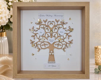 May include: A square wooden shadow box frame containing a decorative tree cutout with white heart-shaped accents. The tree features the text "Golden Wedding Anniversary", "Jim", "Alicia", "18th July 1976", and "50 Years". Embellished with small flowers, butterflies, and crystals.