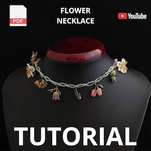 May include: A beaded flower necklace displayed on a black mannequin. The necklace features small, colorful beaded flowers and leaves. The image includes the text "FLOWER NECKLACE" and "TUTORIAL". A PDF icon is in the upper left corner.