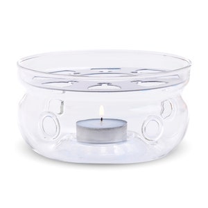 May include: A clear glass tea warmer with a metal insert and a lit tea light candle in the center.
