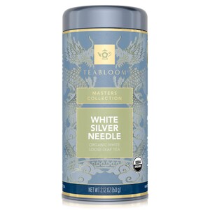 Op de afbeelding: Cilindrische theebus met een lichtblauwe achtergrond en gouden accenten. Het etiket luidt "TEABLOOM MASTERS COLLECTION WHITE SILVER NEEDLE ORGANIC WHITE LOOSE LEAF TEA." Nettogewicht 60 g.