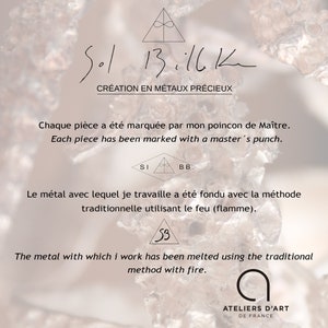 May include: A close-up of a piece of jewelry with the text "Sol 13.11.12" and "Cr&eacute;ation en m&eacute;taux pr&eacute;cieux" in French. The text "Chaque pi&egrave;ce a &eacute;t&eacute; marqu&eacute;e par mon poincon de Ma&icirc;tre." and "Each piece has been marked with a master's punch." is also included. The text "Le m&eacute;tal avec lequel je travaille a &eacute;t&eacute; fondu avec la m&eacute;thode traditionnelle utilisant le feu (flamme)." and "The metal with which I work has been melted using the traditional method with fire." is also included. The text "ATELIERS D'ART DE FRANCE" is also included.