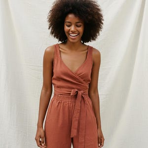 Könnte beinhalten: Ein rostfarbenes Wickeloberteil und eine passende Hose mit weitem Bein. Das Oberteil hat einen V-Ausschnitt und eine Bindung in der Taille. Die Hose hat einen elastischen Bund. Das Outfit ist aus einem weichen, fließenden Stoff gefertigt.