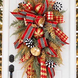 May include: A teardrop-shaped door swag featuring red and gold harlequin ribbons, black and white checkered accents, gold-toned drum ornaments with drumsticks, and green pine branches with gold-colored foliage and black and white spirals.