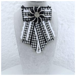 Frauenkrawatte.Farbe schwarz und weiss. Mit einer Brosche Kleidungszubehör verziert.