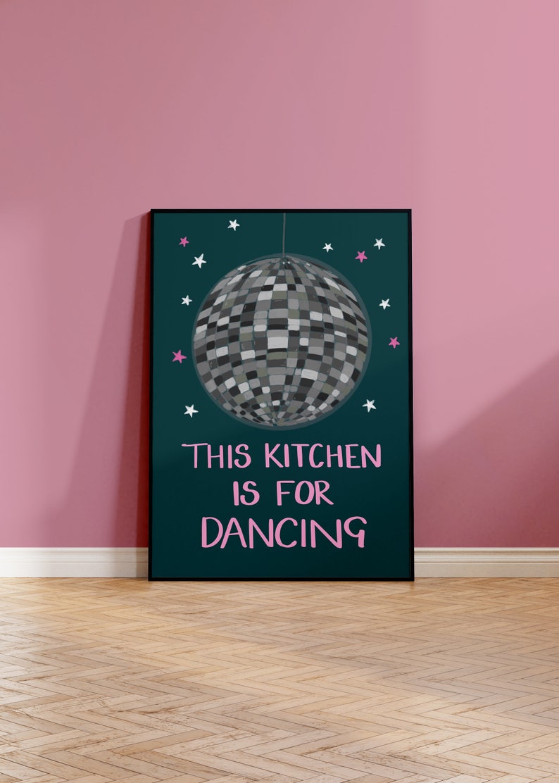 May include: A teal poster with a silver disco ball hanging from the ceiling. The poster has white and pink stars and the text "This kitchen is for dancing" in pink.