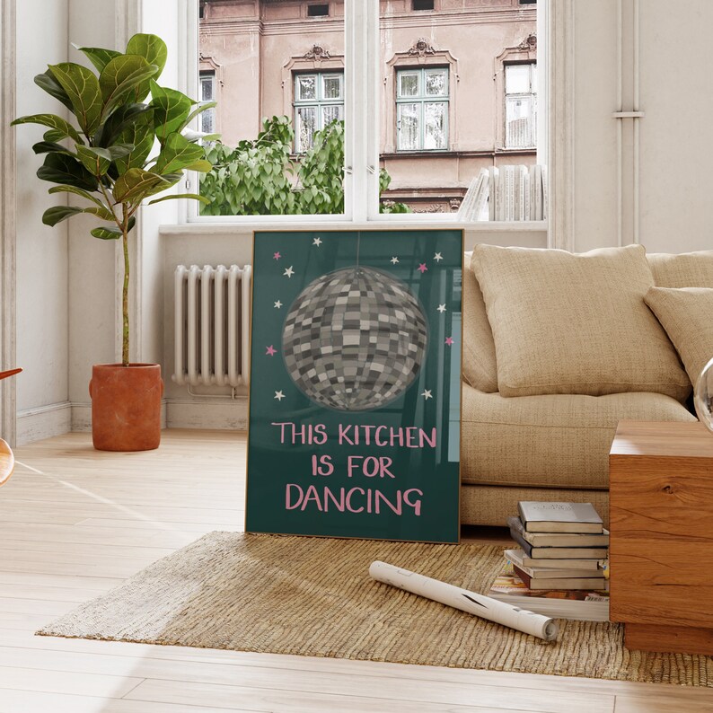 May include: A teal green poster with a silver disco ball and pink stars. The poster says "This kitchen is for dancing."