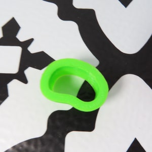 May include: A bright green plastic cookie cutter shaped like a heart with a hole in the center.