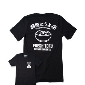 May include: Black t-shirt with a white graphic of a bowl of tofu and the text "藤原とうふ店 (FUJIWARA TOFU SHOP)" and "FRESH TOFU DELIVERED NIGHTLY".