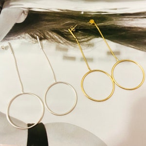 May include: Two pairs of dangle earrings with a circle pendant. One pair is gold and the other is silver.