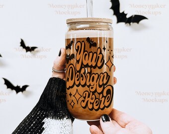 May include: A glass jar with a brown lid and a clear straw. The jar has a design on it that says "Your Design Here" in orange and black lettering. The jar is being held by a person wearing a black and white sweater.