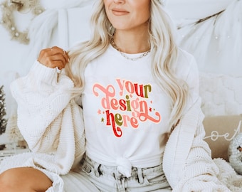 May include: A white t-shirt with a colorful design that says "your design here" in a retro font. The shirt is being worn by a person with long blonde hair.