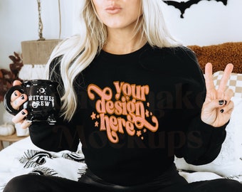 May include: A black sweatshirt with the text "Your design here" in pink and orange lettering. The sweatshirt is being modeled by a person wearing black leggings and a brown beanie.