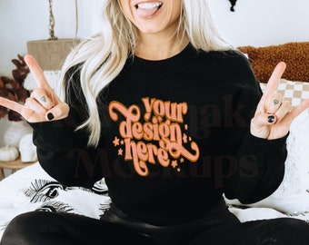 May include: A black sweatshirt with the text "Your design here" in pink lettering. The model is wearing the sweatshirt with black leggings and white shoes.