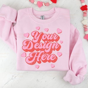 May include: Pink sweatshirt with the text "Your Design Here" in a retro font with red and pink hearts.