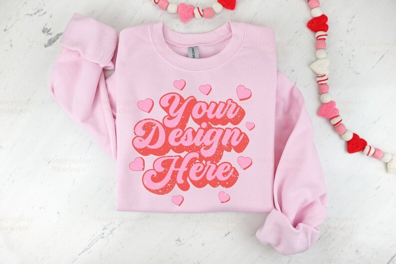 May include: Pink sweatshirt with the text "Your Design Here" in a retro font with red and pink hearts.