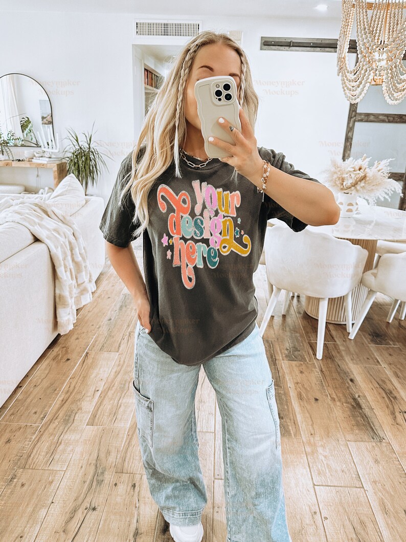 May include: A black t-shirt with the text "Your design here" in colourful letters. The shirt is being worn by a person with long blonde hair and blue jeans.