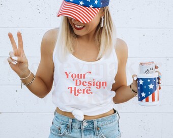 Könnte beinhalten: Eine Frau trägt ein weißes Tanktop mit dem Text "Your Design Here" in roten Buchstaben. Sie trägt eine rot-weiß-blaue Baseballkappe und hält eine rot-weiß-blaue Getränkedose.