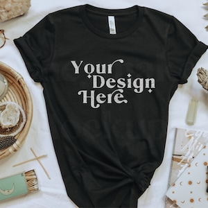May include: A black t-shirt with the text "Your Design Here" in white on the front. The shirt is laid flat on a white surface with various decorative items around it.