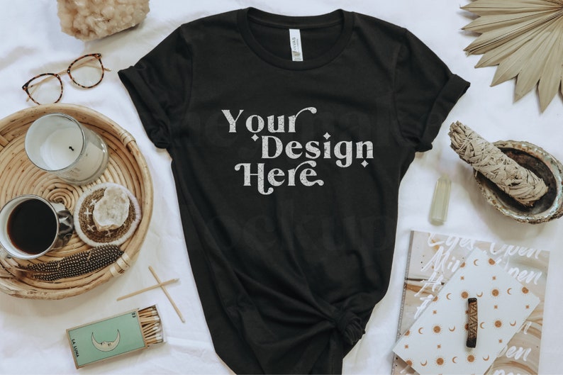 May include: A black t-shirt with the text "Your Design Here" in white on the front. The shirt is laid flat on a white surface with various decorative items around it.