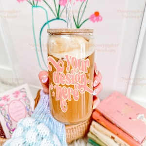 Può includere: Una tazza di vetro con un coperchio di legno e una cannuccia, piena di caffè freddo. La tazza ha un adesivo rosa e oro che dice "Your design here".