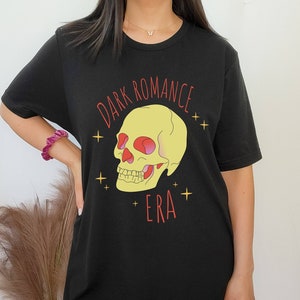 Peut inclure: T-shirt noir surdimensionné avec un motif de crâne jaune et le texte "DARK ROMANCE ERA" en rouge.