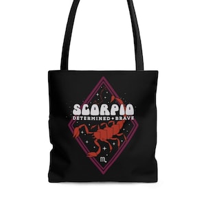 May include: Black tote bag with black handles. The bag features a red and white graphic of the Scorpio zodiac sign, with the words "SCORPIO DETERMINED + BRAVE" in white text. The design is set within a purple diamond.