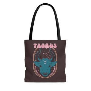 May include: Brown tote bag with black handles featuring a teal bull illustration with the word "TAURUS" in pink. The design includes the Taurus constellation and the words "Dependable" and "Persistent".