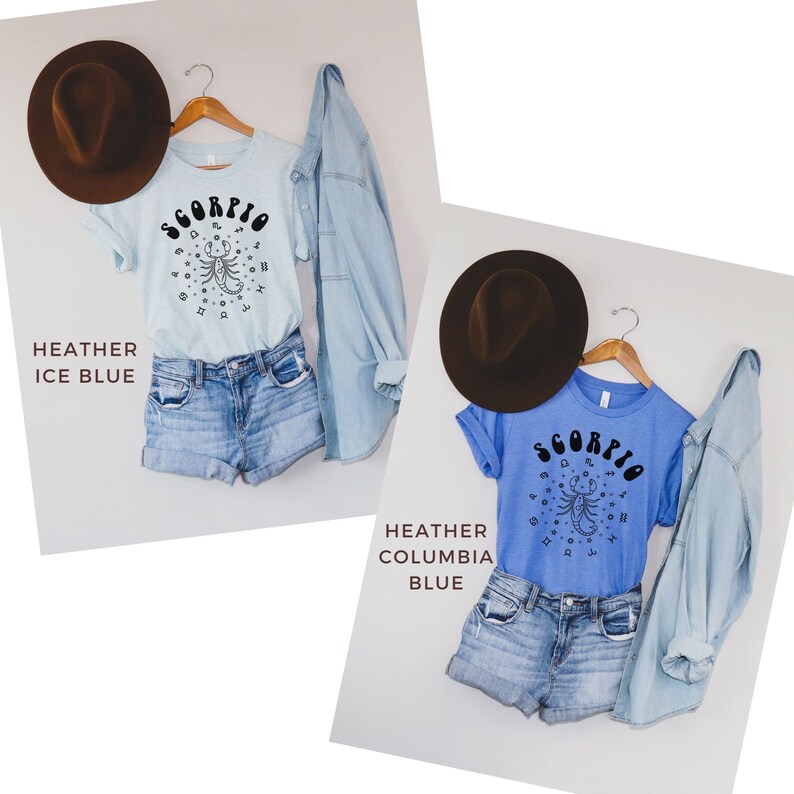May include: Two t-shirts with a scorpion graphic and the word "Scorpio" in a retro font. The shirt on the left is light blue and the shirt on the right is blue. Both shirts are on hangers and are styled with denim shorts and a brown hat.