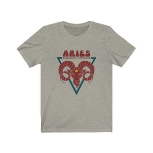 May include: A heather grey t-shirt with a graphic of a ram's head in a triangle with the text "Aries" in a retro font and the words "Passionate - Confident" below.