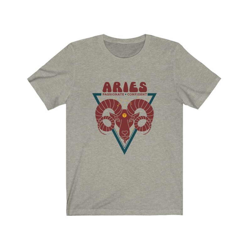 May include: A heather grey t-shirt with a graphic of a ram's head in a triangle with the text "Aries" in a retro font and the words "Passionate - Confident" below.