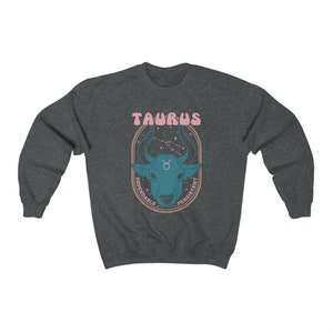May include: A dark gray sweatshirt with a graphic of a blue bull's head with a pink Taurus sign and the words "Dependable" and "Persistent" in a circle around the bull's head.