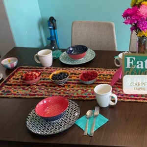 Southwestern style table runner with vivid rainbow hues on a jute base, ideal for boho interiors

Durable handmade jute runner for tables, featuring a mix of cotton fabric strips and earthy texture