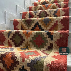 May include: A set of colourful, geometric patterned jute rugs, placed on a set of stairs. The rugs are made of natural fibres and have a rustic, bohemian style. The text "Luxury Beneath Feet" is visible in the bottom right corner of the image.