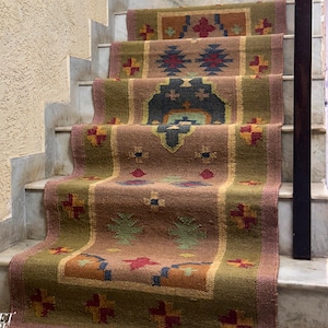 May include: A brown, green, and red patterned rug with fringe on the bottom edge. The rug is laid out on a set of stairs.