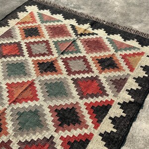 Jute Wool Rug handloomed in traditional flatweave featuring stepped-diamond motifs in rust, ochre, sage and plum — a Kilim Area Rug crafted in India.