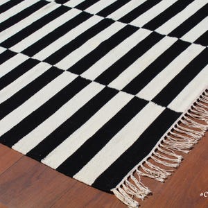 This handwoven wool rug blends traditional craftsmanship with modern aesthetics, making it a timeless choice for any decor style. The striped design offers a sleek, structured look, perfect for monochrome lovers. Whether you need a statement piece for your living room or a functional runner for high-traffic areas, this versatile wool rug delivers both beauty and durability.