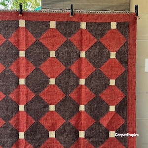 Red kilim flatweave area rug crafted from natural wool and jute fibers, designed with eye-catching geometric patterns inspired by Southwestern and Navajo textile traditions. This handmade rug complements farmhouse, global, or vintage-style decor and brings a cozy, artisanal touch to entryways, bedrooms, or under a coffee table.