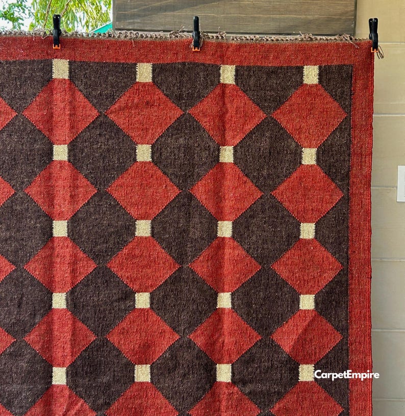 Red kilim flatweave area rug crafted from natural wool and jute fibers, designed with eye-catching geometric patterns inspired by Southwestern and Navajo textile traditions. This handmade rug complements farmhouse, global, or vintage-style decor and brings a cozy, artisanal touch to entryways, bedrooms, or under a coffee table.