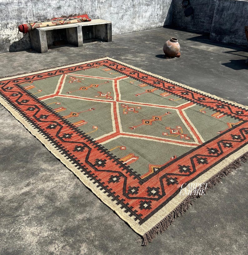 Handwoven Moroccan kilim rug in sage green with terracotta diamond medallions tribal motifs and multi band zigzag border. Wool jute flatweave. Custom area rug sizes India.