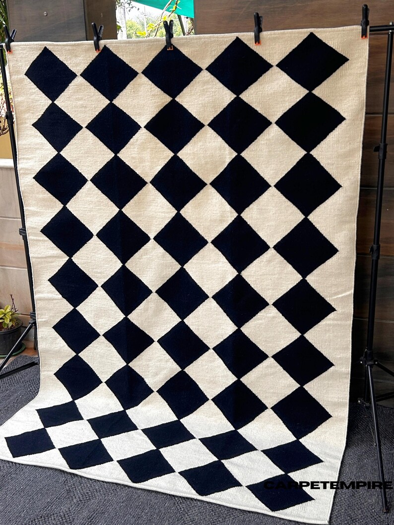 Black and white checkered wool area rug crafted with a geometric diamond pattern. This handwoven rug adds texture and visual balance to any modern room, combining luxurious wool softness with artisan craftsmanship. Ideal for flatweave lovers and sustainable home design.