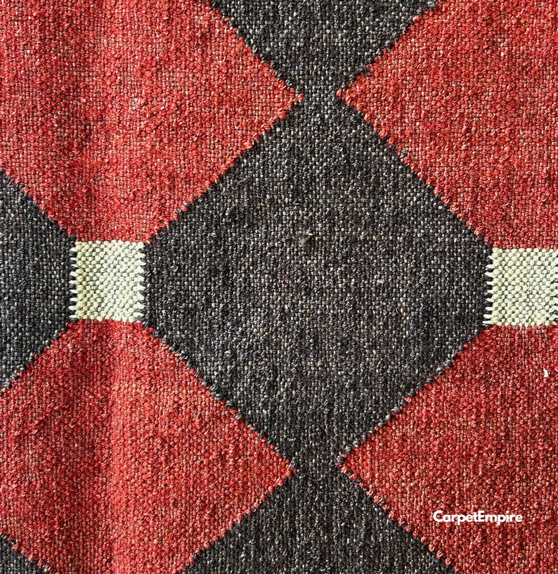 Geometric handwoven kilim rug crafted in red, mustard, and brown hues using traditional wool and jute fibers. Inspired by vintage Navajo and Southwestern rugs, this dhurrie is flatwoven and reversible, ideal for decorating rustic cabins, cozy farmhouses, or contemporary apartments with artisanal character.