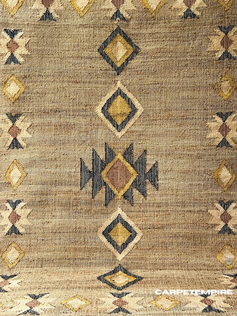 Subtle beige cream jute rug with geometric kilim pattern and dark border for definition, hand‑crafted in natural fiber flatweave. Earthy texture and neutral palette enhance rustic, cottage, or Scandi interiors. Offers a calming foundation — soft tones underfoot, artisanal weave, and versatile enough to match wood or metal accents while maintaining serenity in the space.
