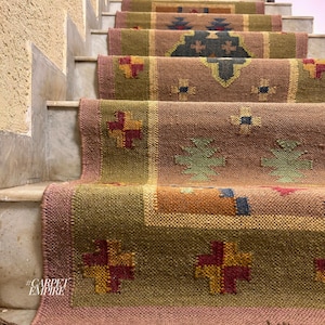 May include: A set of colorful patterned rugs on a staircase. The rugs are made of woven fabric and have a variety of geometric designs. The rugs are in shades of brown, green, red, and yellow. #CARPETEMPIRE