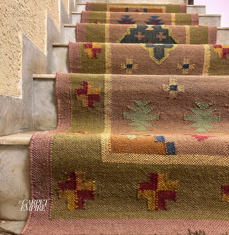 May include: A set of colorful patterned rugs on a staircase. The rugs are made of woven fabric and have a variety of geometric designs. The rugs are in shades of brown, green, red, and yellow. #CARPETEMPIRE