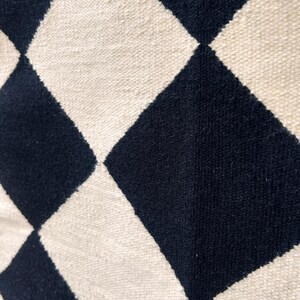 Contemporary geometric checkered wool rug in black and white. Handwoven using natural wool, it provides a soft texture and minimalist appeal suited for living rooms, bedrooms, or workspaces. The flatweave design adds both style and durability to everyday use.