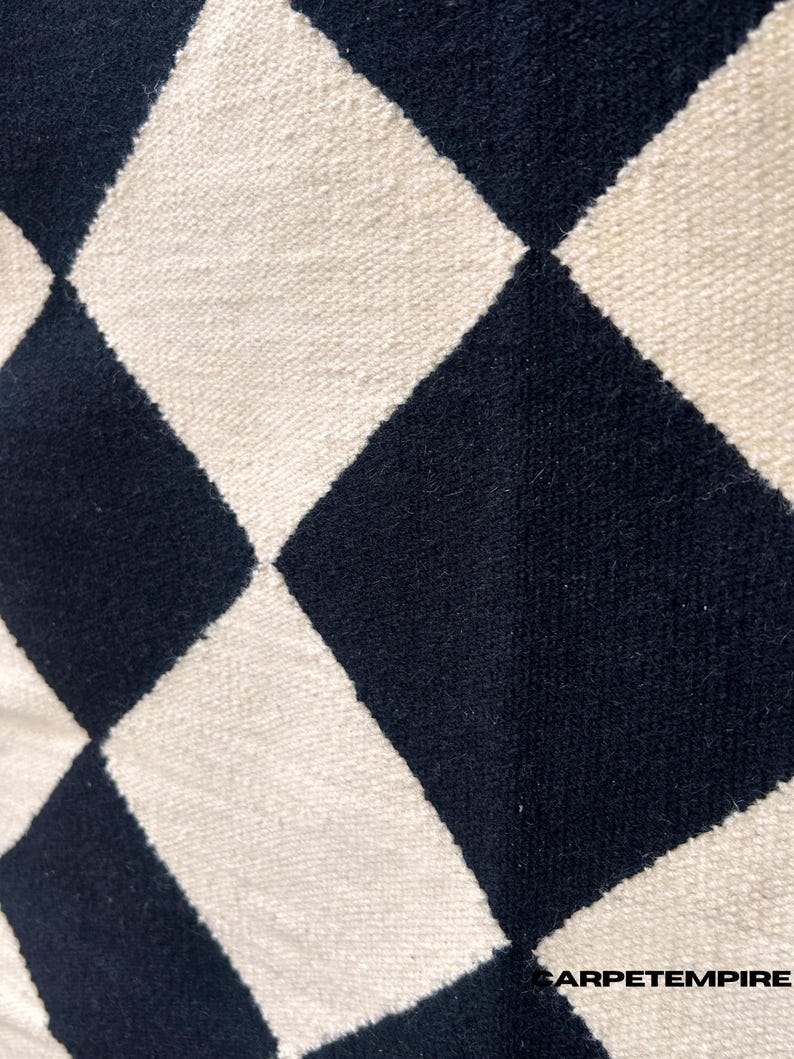 Contemporary geometric checkered wool rug in black and white. Handwoven using natural wool, it provides a soft texture and minimalist appeal suited for living rooms, bedrooms, or workspaces. The flatweave design adds both style and durability to everyday use.