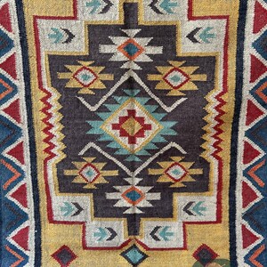 May include: A colorful rug with a geometric pattern in shades of red, blue, yellow, and white. The rug has a dark brown background and a border of blue, red, and white triangles.